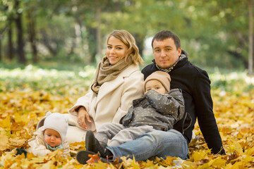 Fototapeta premium Beautiful young family with children in the autumn park. Love and tenderness. Active recreation in nature.
