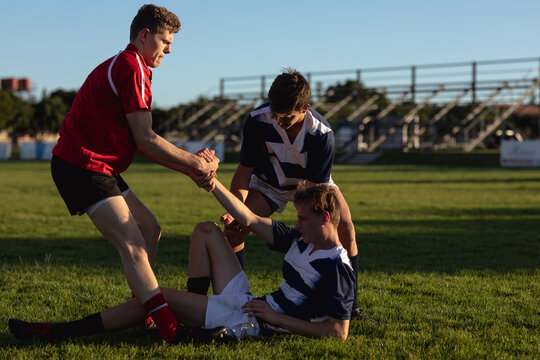 Rugby players helping a player on the ground - Powered by Adobe