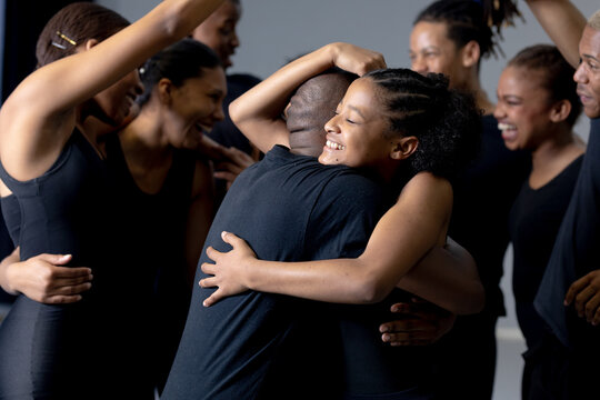 Mixed race modern dancers hugging each other in a studio
