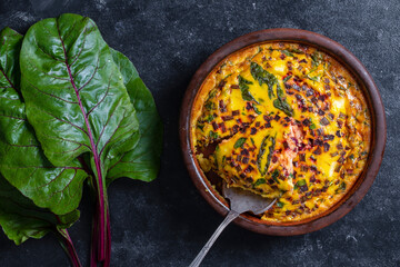 Ceramic bowl with vegetable frittata. Frittata with eggs, green beet leaves, onion, pepper, spices and cheese - Powered by Adobe