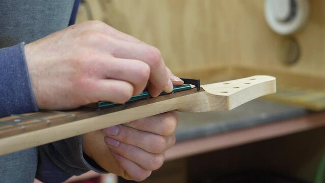 Close up of making the nut on newly built electric resonator guitar. Slow motion.