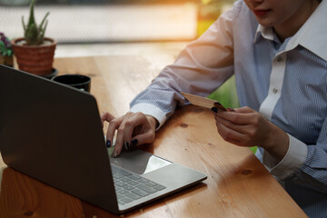 Young person using credit card and laptop computer. Online shopping, e-commerce concept