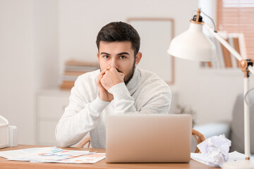 Young bearded man working on laptop at home