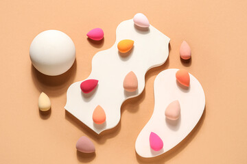 Stands with makeup sponges on beige background