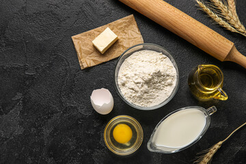 Composition with ingredients for baking and rolling pin on dark background