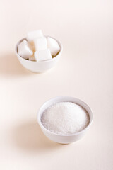 Granulated sugar and sugar cubes in bowls. Choosing between types of sugar. Vertical view