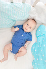 baby boy in a cot among pillows, concept of baby linen and textiles
