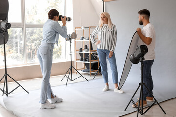 Female photographer and her assistant working with mature woman in studio