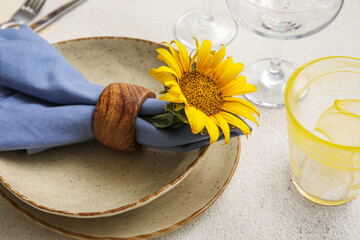 Dinnerware and beautiful sunflower in plate on light table, closeup