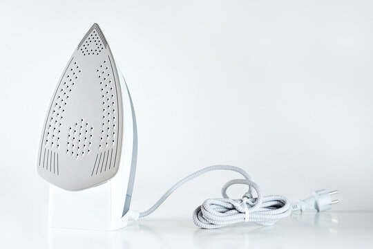 New iron with electrical cable on white background, Modern household appliances to help with daily routine and chores
