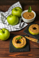 Tasty apple rounds with nut butter on wooden table