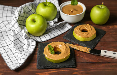 Tasty apple rounds with nut butter on wooden table