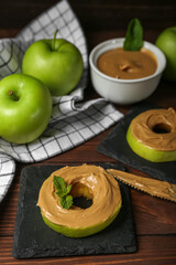 Tasty apple rounds with nut butter on wooden table, closeup