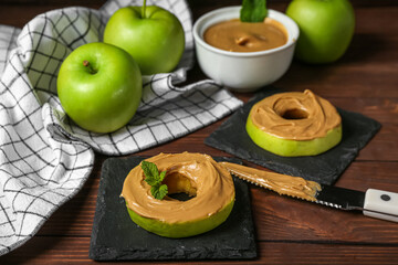 Tasty apple rounds with nut butter on wooden table, closeup