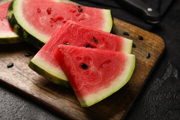 Cutting board with slices of tasty watermelon on dark background, closeup