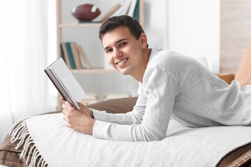 Teenage boy reading book in bedroom