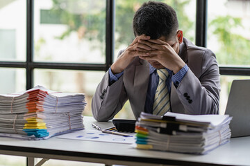 A busy businessman sleeps at his desk with his financial calculators and papers piled up on a pile...