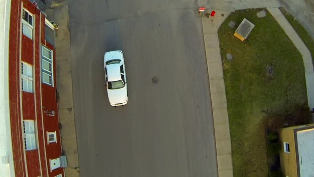 Aerial Top Backwards Shot Of White Car Moving On Street In City - Buckner, Missouri