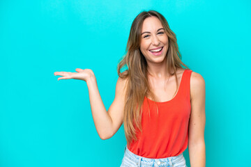 Young caucasian woman isolated on blue background holding copyspace imaginary on the palm to insert an ad