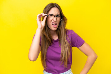 Young caucasian woman isolated on yellow background With glasses and frustrated expression