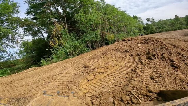 POV while operating a skid steer loader to move small pile of dirt to level a large pond construction site