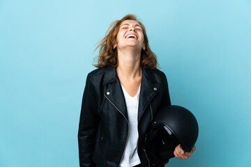 Georgian girl holding a motorcycle helmet isolated on blue background laughing