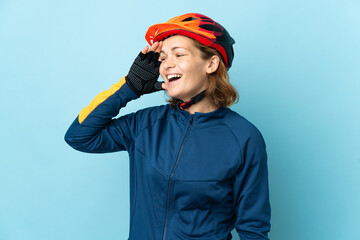 Young cyclist woman isolated on blue background smiling a lot