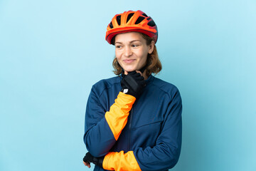 Young cyclist woman isolated on blue background looking to the side and smiling