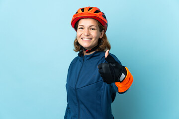 Young cyclist woman isolated on blue background with thumbs up because something good has happened