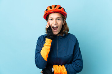 Young cyclist woman isolated on blue background with surprise and shocked facial expression