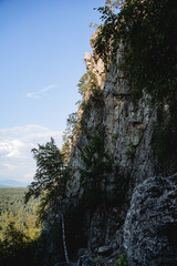 a mountain range in the forest, a rock illuminated by the sun, a landscape of tourist attractions, a protected route, the stone walls of the mountain.