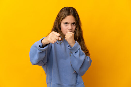 Child over isolated yellow background with fighting gesture