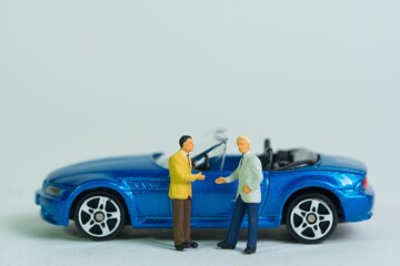 Car sale by handshake,  blue cabriolet sports car, miniature figure scene, toy car