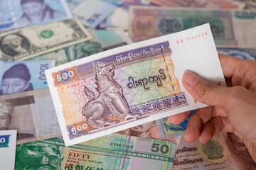 hand hold Myanmar banknote with international banknotes in a background