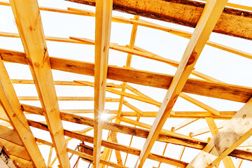 The construction of a wooden roof from large beams and boards. View from bottom to top. Unfinished