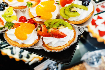 Small cakes with strawberries and kiwi. Manufacture and trade of confectionery. Close-up