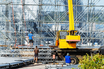 Assembling a concert stage using heavy equipment and a crane. Close-up