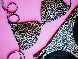 Closeup of a flat lay with a leopard bikini on pink background