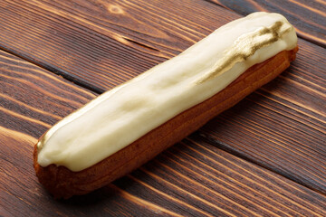 Eclairs with vanilla glaze on a wooden board