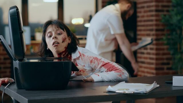 Stupid spooky looking monster trying to use printer machine. Creepy evil brain dead zombie with deep and bloody scars and wounds while damaging scanner machine in company office workspace.
