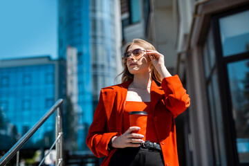 Fototapeta premium woman in formal suit enjoying sunny day and walking near the skyscrapers during