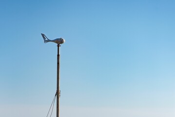 Plane-type anemometer on a post against a blue sky background