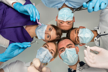 A large group of motivated doctors and nurses standing in a circle and joking with each other.