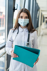 nurse in blue wearing a medical mask . writes down information about the patient