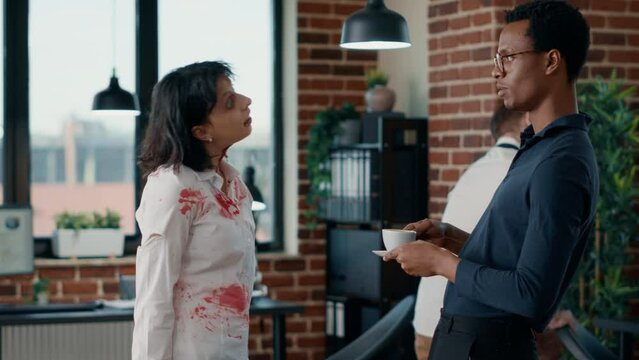 Brain dead zombie woman touching businessman while discussing. Doomsday survivor talking with dangerous dead walking corpse having bloody and deep wounds in office workspace.