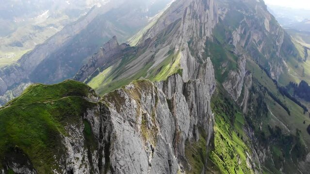 Aerial flyover over the cliffs of Schafler ridge in Appenzell, Switzerland with pan up towards the mountains including Altenalpturm