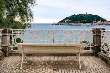 Obraz premium A couple on la Concha promenade bench with a view the bay in San Sebastian Spain