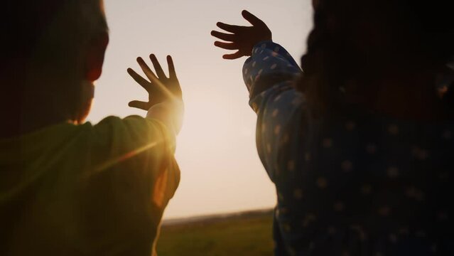 happy family kids people group pull hands to the sun teamwork. silhouette people party dancing recreation holiday. kids at a lifestyle music concert pull their hands up. religion concept sunlight