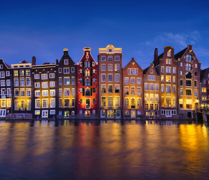 Damrak, Amsterdam, Netherlands. View of houses during sunset. The famous Dutch canals. A cityscape in the evening. Travel photography.