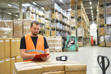 friendly warehouse worker in a warehouse with the barcode scanner - 528387840